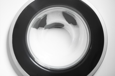 Photo of Washing machine with suds as background, closeup