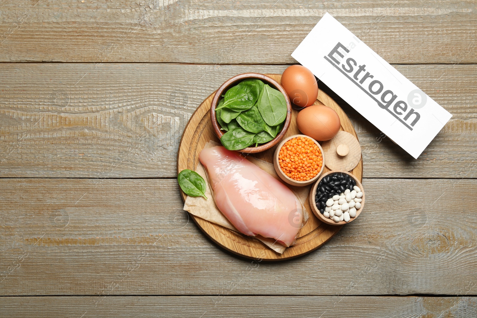 Photo of Word Estrogen and products on wooden table, top view. Space for text