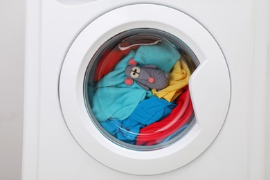 Photo of Washing machine with clothes and toy rat as background, closeup