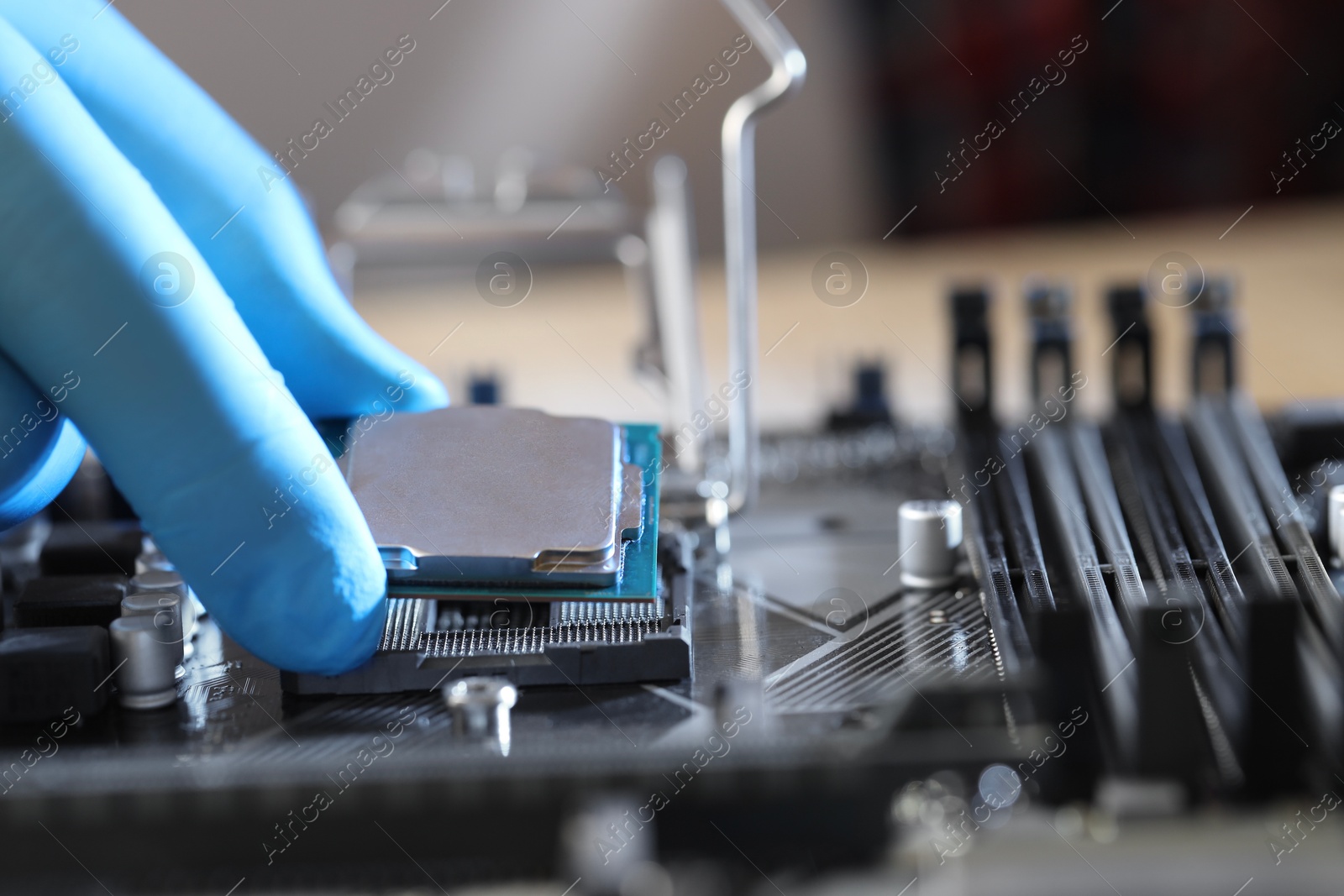 Photo of Man installing computer chip onto motherboard at table, closeup