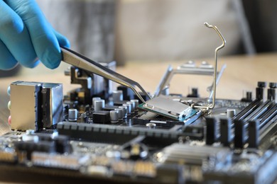 Photo of Man installing computer chip onto motherboard at table, closeup