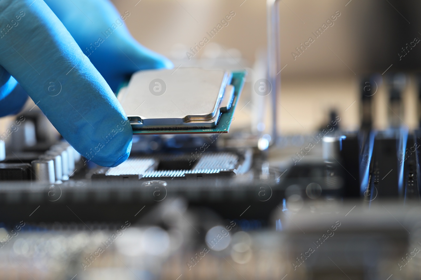 Photo of Man installing computer chip onto motherboard at table, closeup