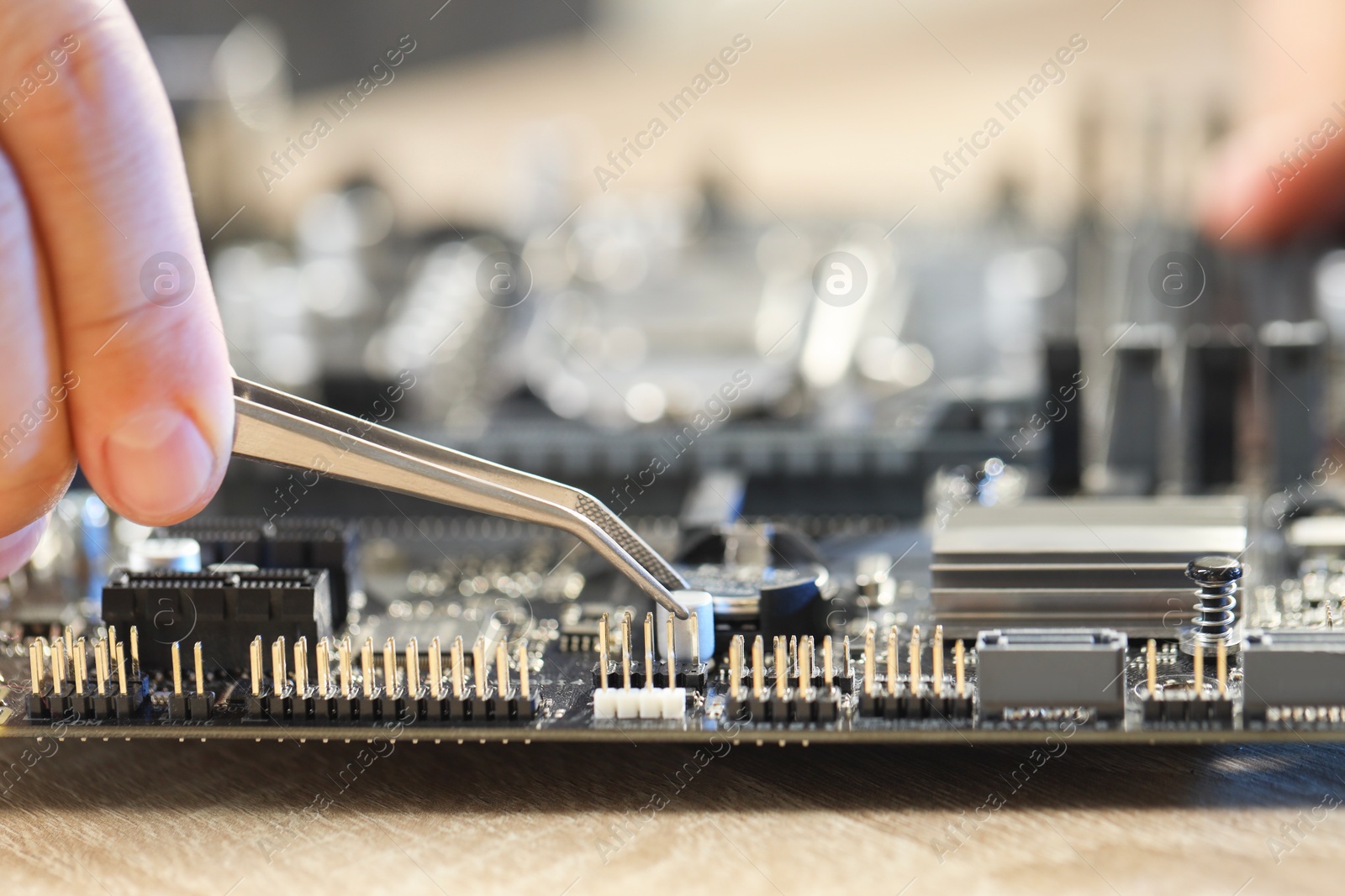 Photo of Man installing computer chip onto motherboard at wooden table, closeup