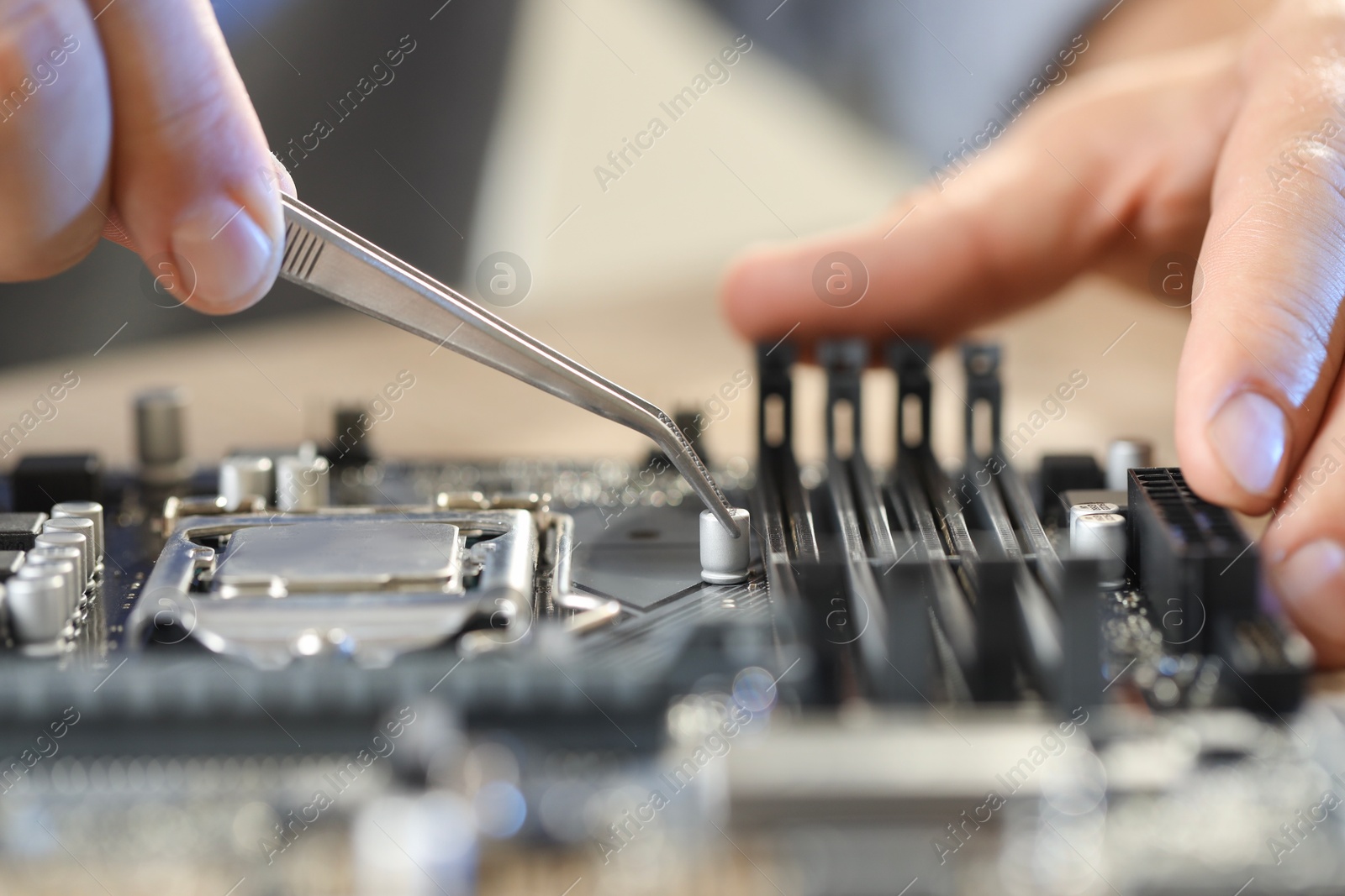 Photo of Man installing computer chip onto motherboard at table, closeup