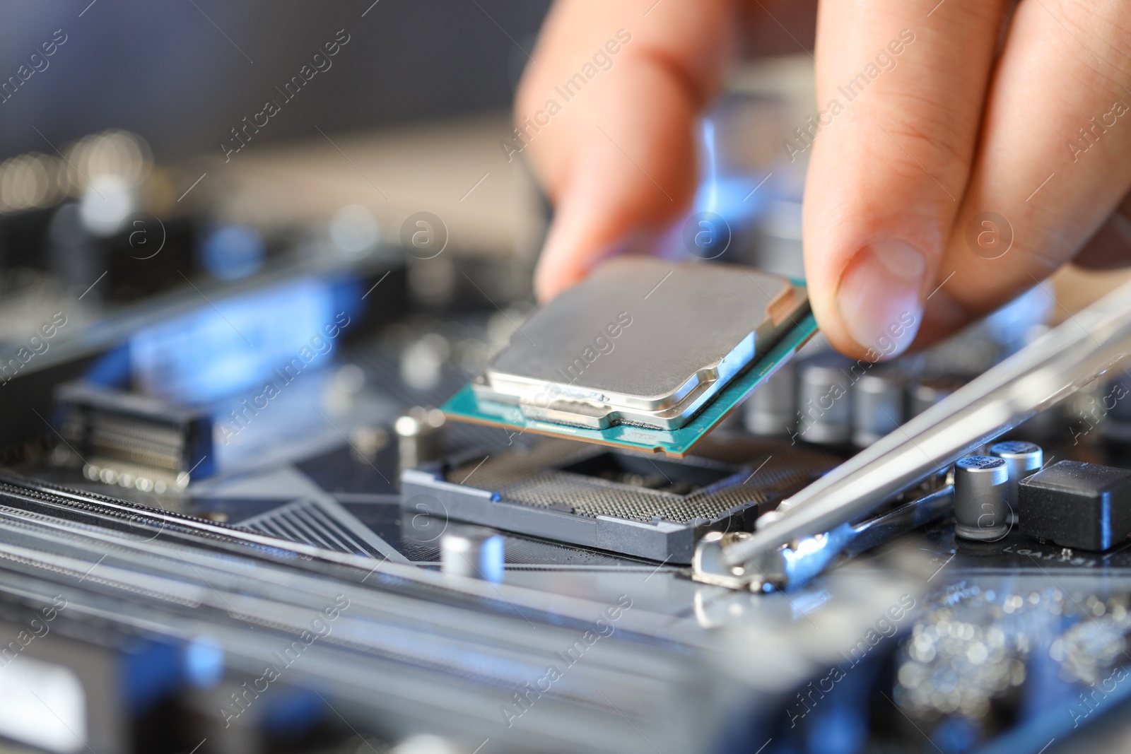 Photo of Man installing computer chip onto motherboard at table, closeup