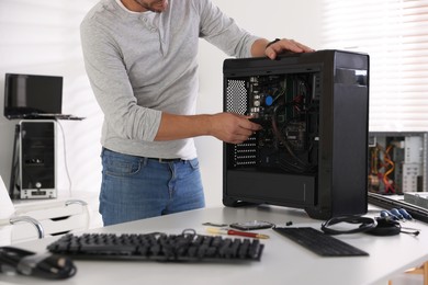 Photo of Man assembling new computer at white table, closeup