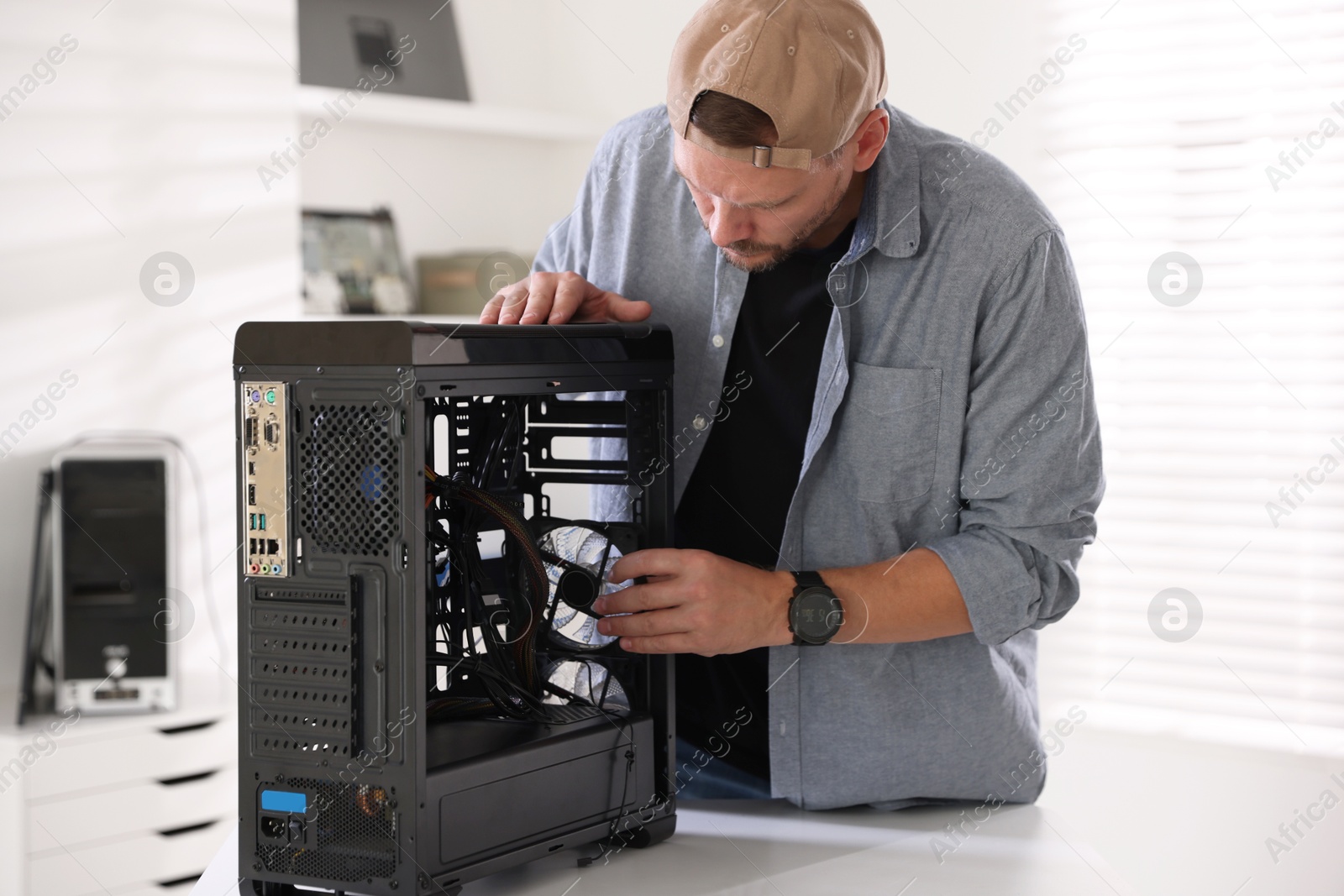 Photo of Man installing fan into computer at white table