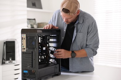 Photo of Man installing fan into computer at white table