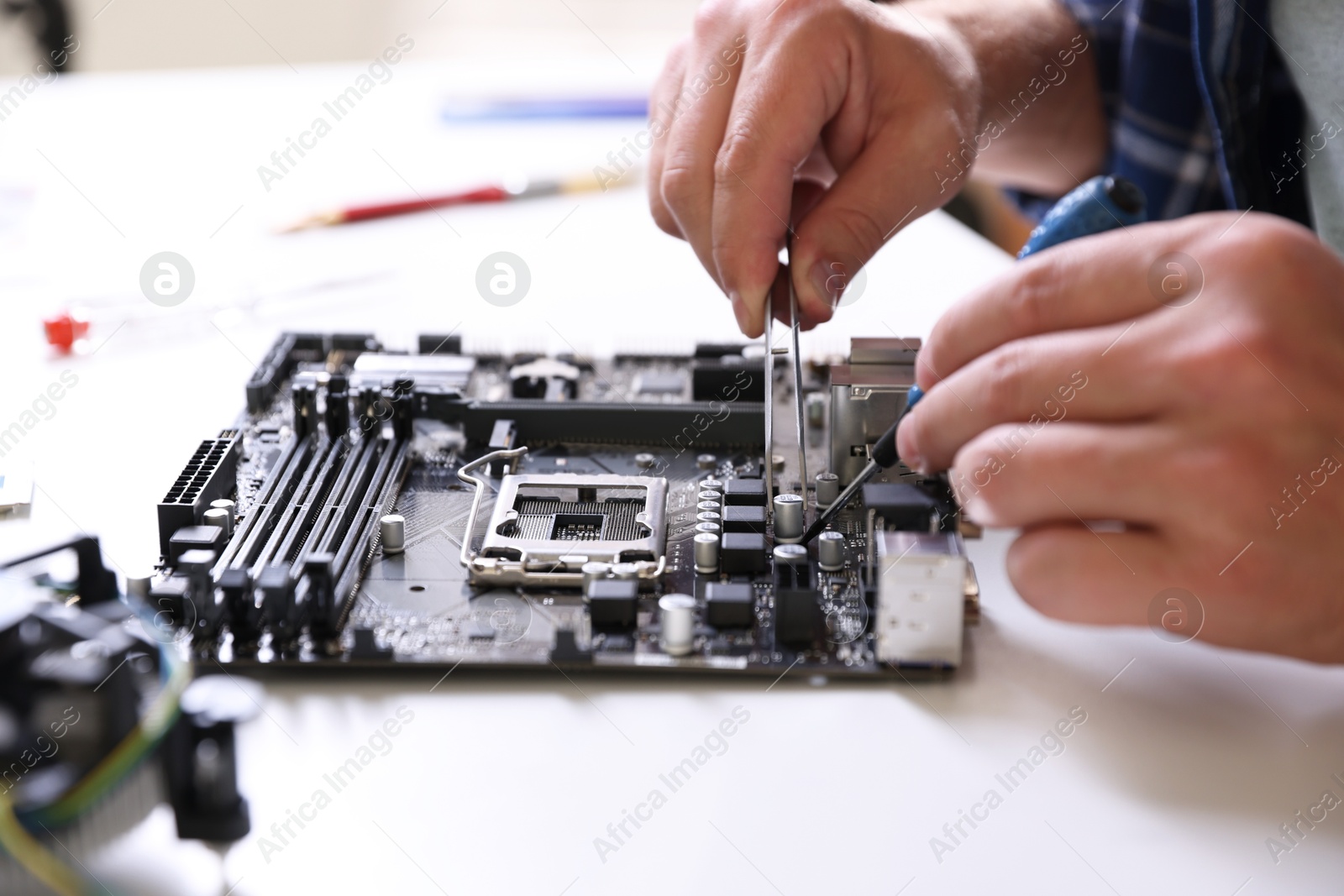 Photo of Man installing computer chip onto motherboard at white table, closeup