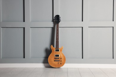 Photo of One modern electric guitar near grey wall