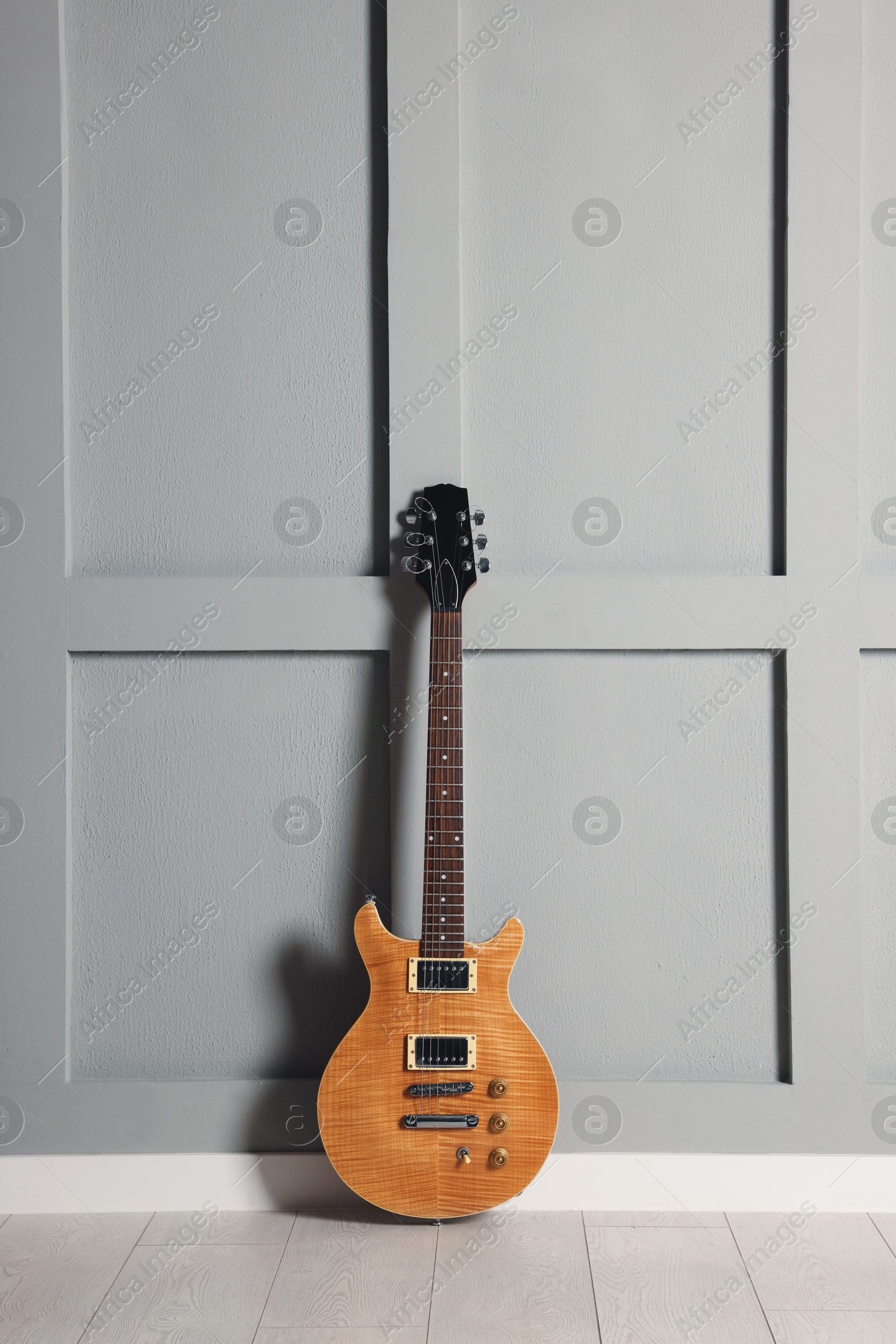 Photo of One modern electric guitar near grey wall