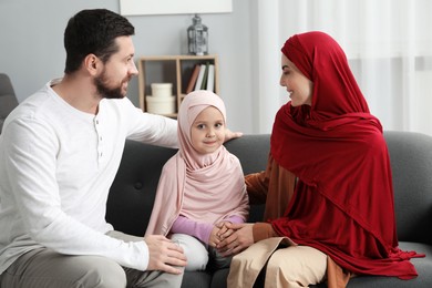 Happy Muslim family sitting on sofa at home