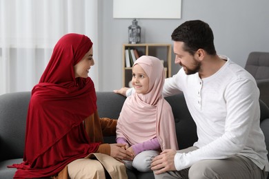 Happy Muslim family sitting on sofa at home