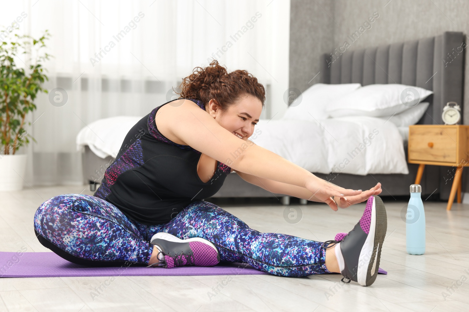 Photo of Plus size woman stretching during fitness training at home