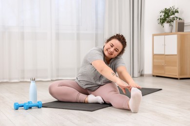 Photo of Plus size woman exercising on fitness mat at home