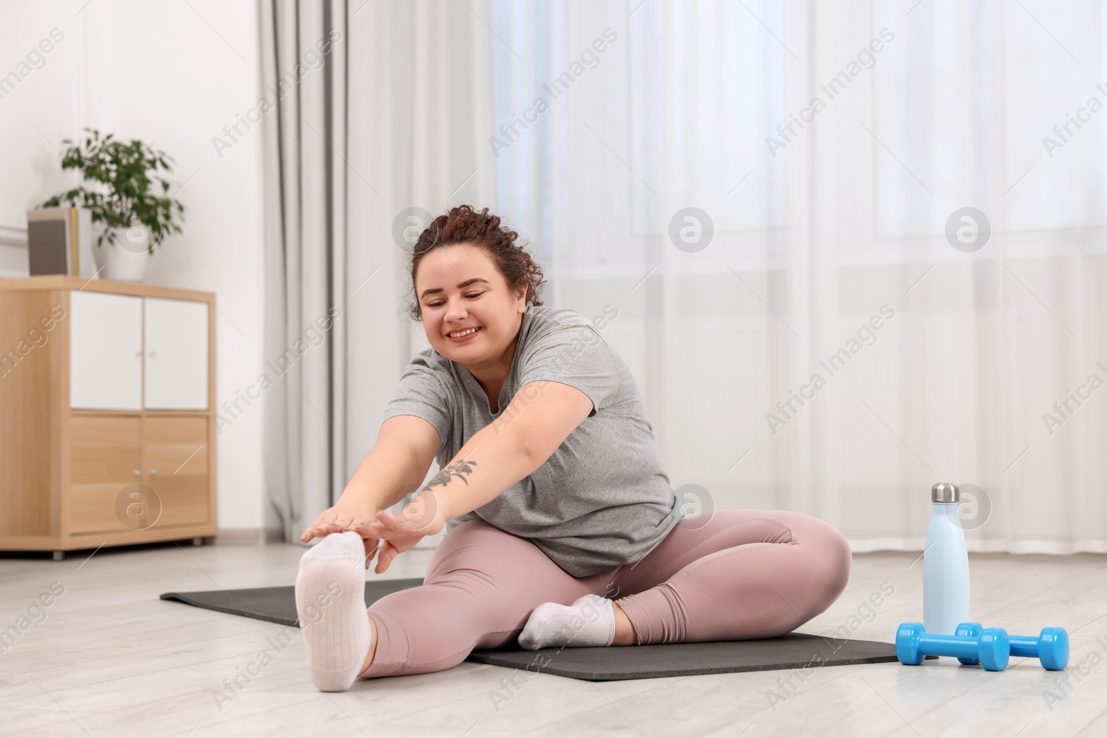 Photo of Plus size woman exercising on fitness mat at home