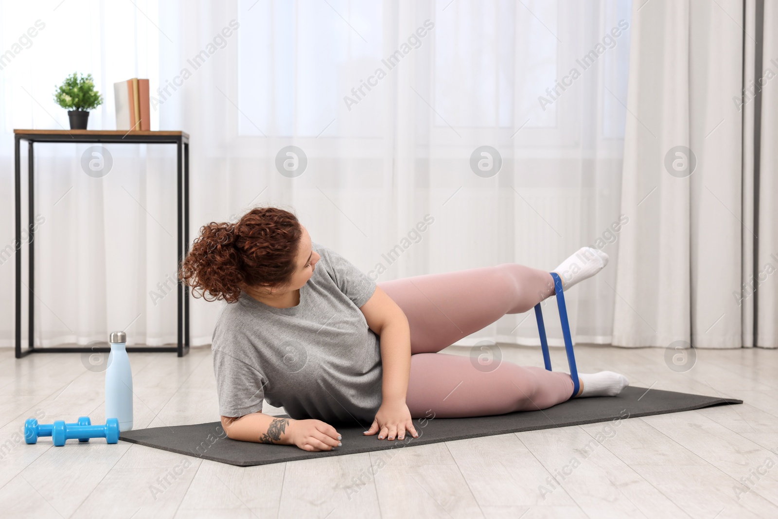 Photo of Woman training with resistance band at home