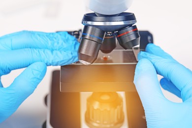 Scientist examining sample on slide under microscope, closeup