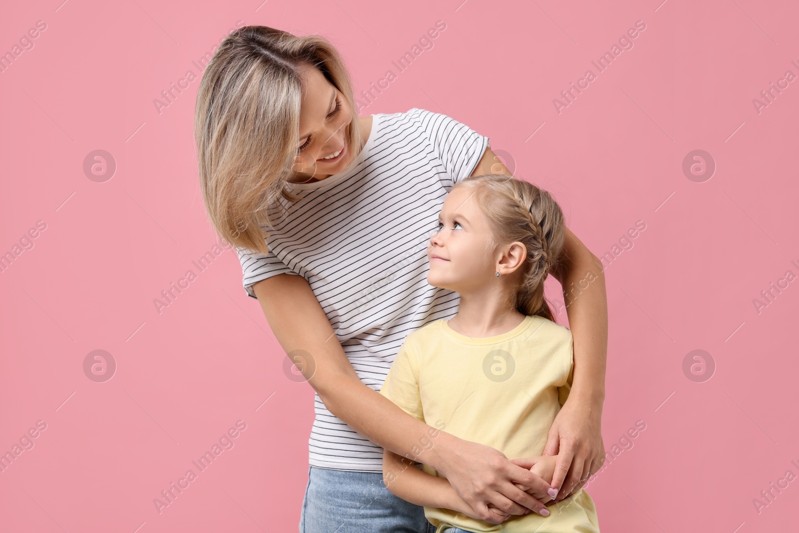 Photo of Cute little girl with her mom on pink background. Happy Mother's Day