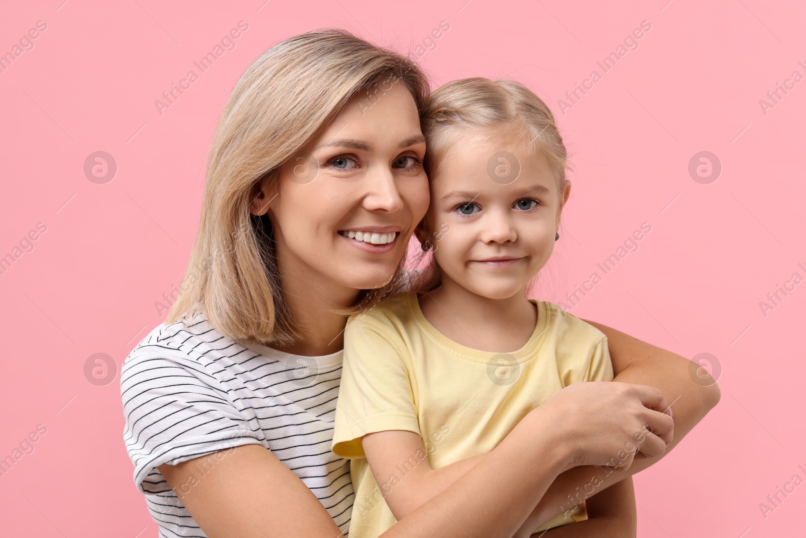 Photo of Cute little girl with her mom on pink background. Happy Mother's Day