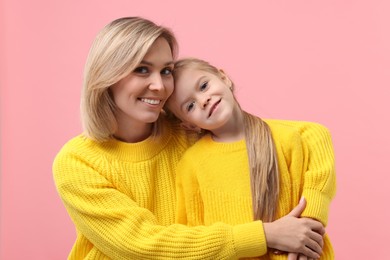 Photo of Cute little girl with her mom on pink background. Happy Mother's Day