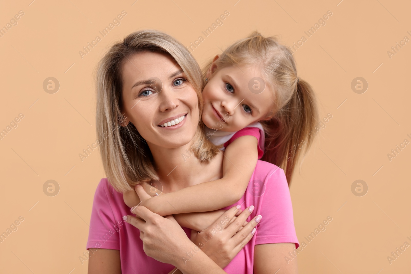 Photo of Cute little girl hugging her mom on beige background. Happy Mother's Day