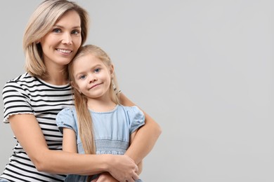 Photo of Cute little girl with her mom on gray background, space for text. Happy Mother's Day