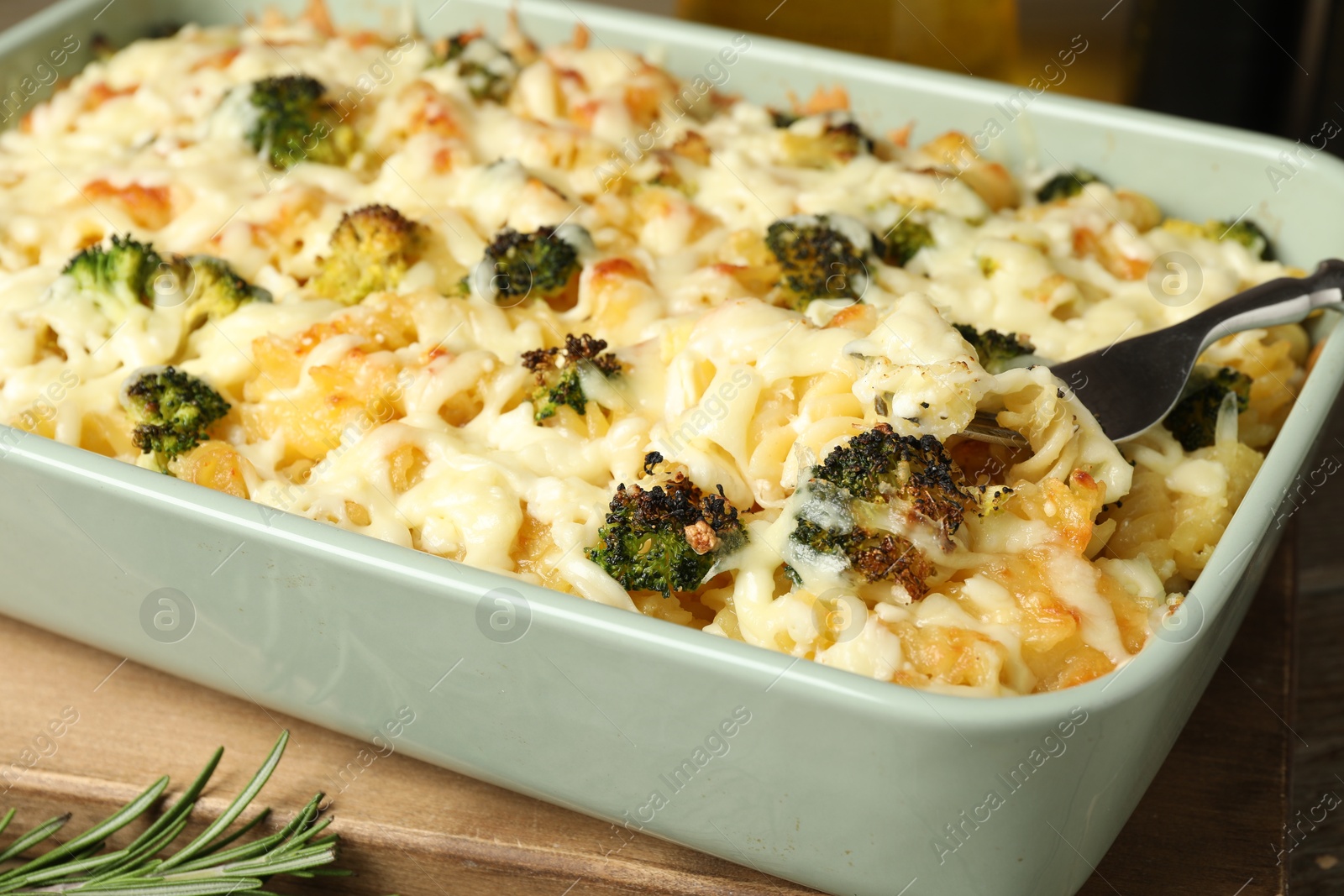 Photo of Tasty pasta casserole with cheese and broccoli in baking dish on wooden table, closeup