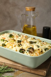 Photo of Tasty pasta casserole with cheese and broccoli in baking dish on wooden table, closeup