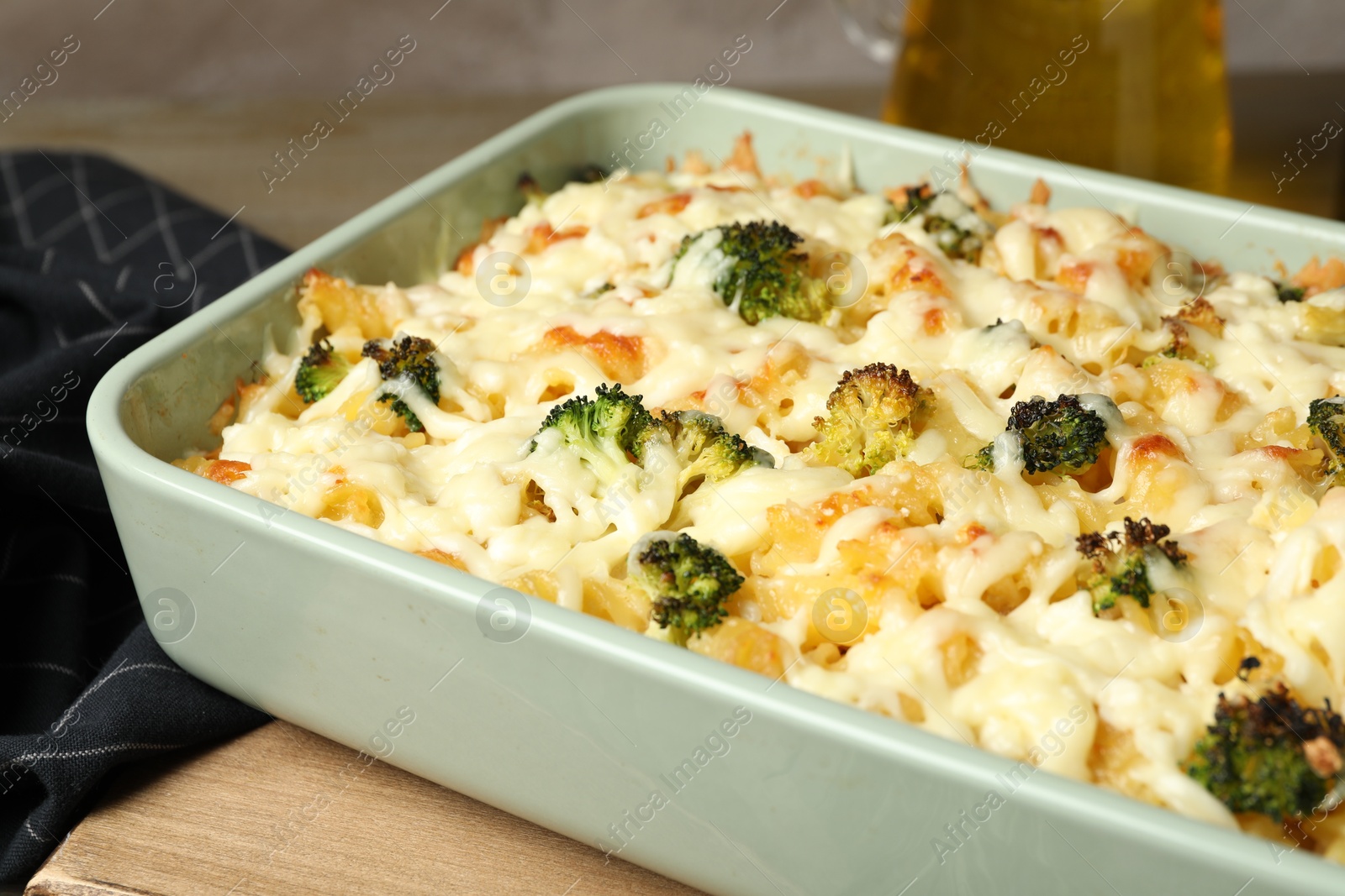 Photo of Tasty pasta casserole with cheese and broccoli in baking dish on wooden table, closeup