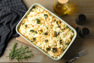 Photo of Tasty pasta casserole with cheese and broccoli in baking dish on wooden table, flat lay