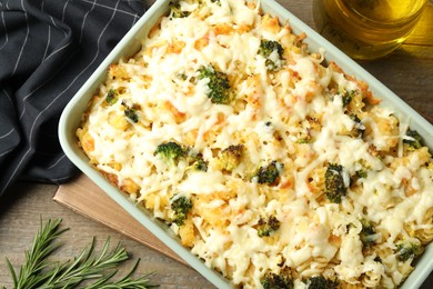 Photo of Tasty pasta casserole with cheese and broccoli in baking dish on wooden table, flat lay