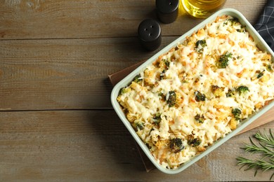 Photo of Tasty pasta casserole with cheese and broccoli in baking dish on wooden table, flat lay. Space for text