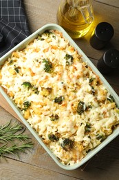 Photo of Tasty pasta casserole with cheese and broccoli in baking dish on wooden table, flat lay