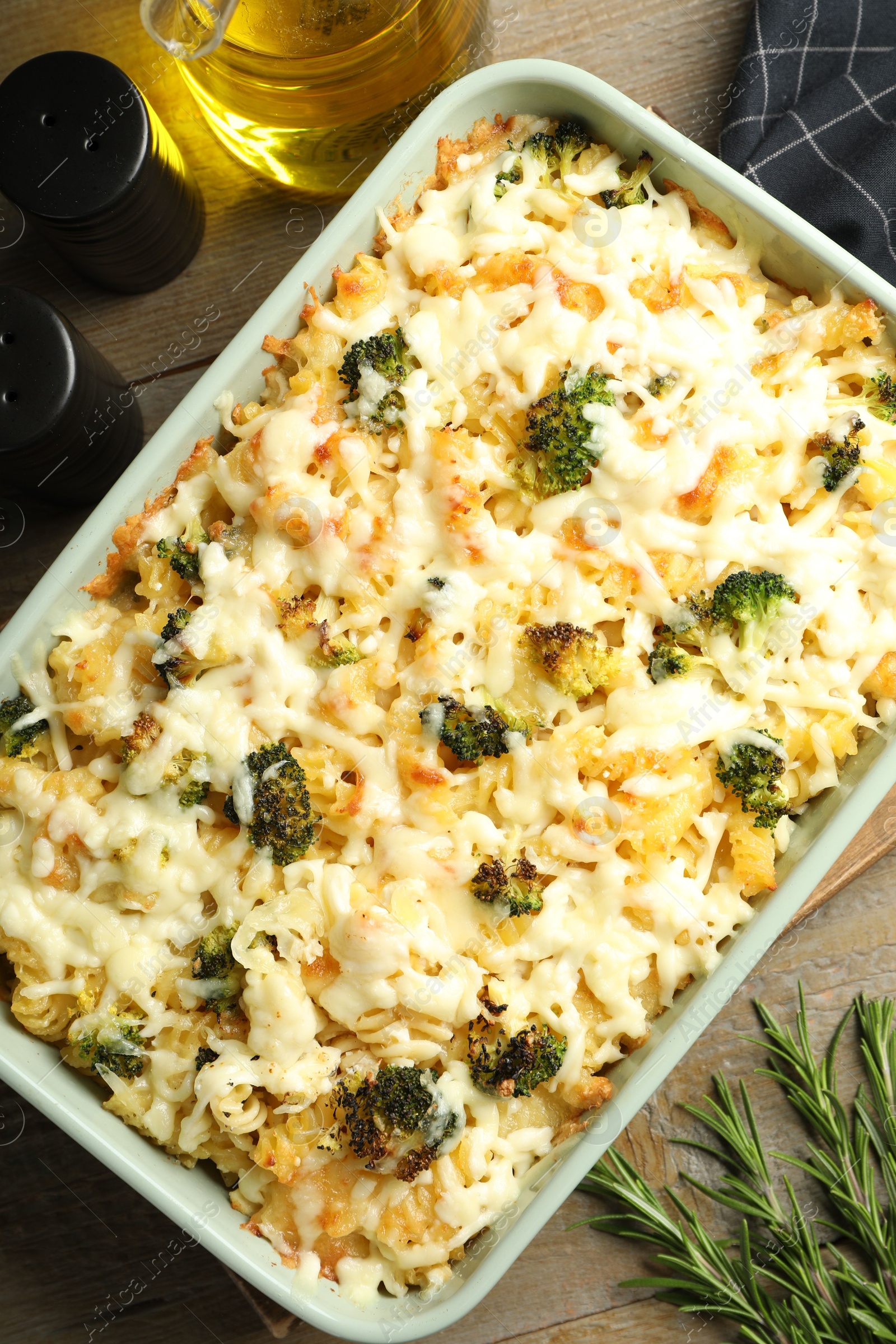 Photo of Tasty pasta casserole with cheese and broccoli in baking dish on wooden table, flat lay