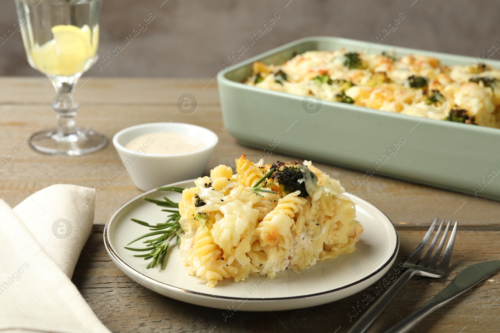 Photo of Tasty pasta casserole with cheese and broccoli served on wooden table