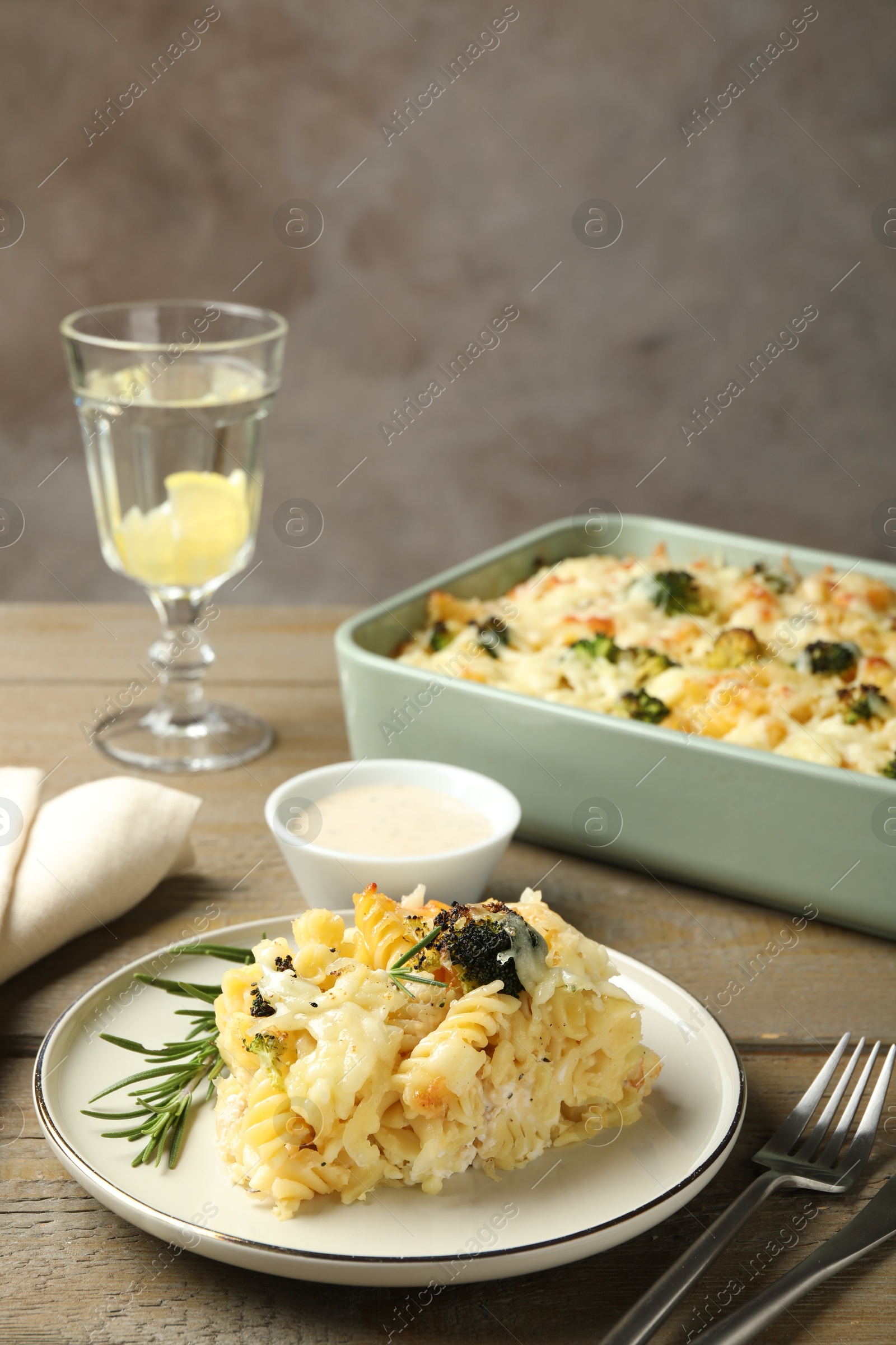 Photo of Tasty pasta casserole with cheese and broccoli served on wooden table