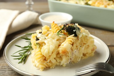 Photo of Tasty pasta casserole with cheese and broccoli served on wooden table, closeup