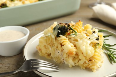 Photo of Tasty pasta casserole with cheese and broccoli served on wooden table, closeup