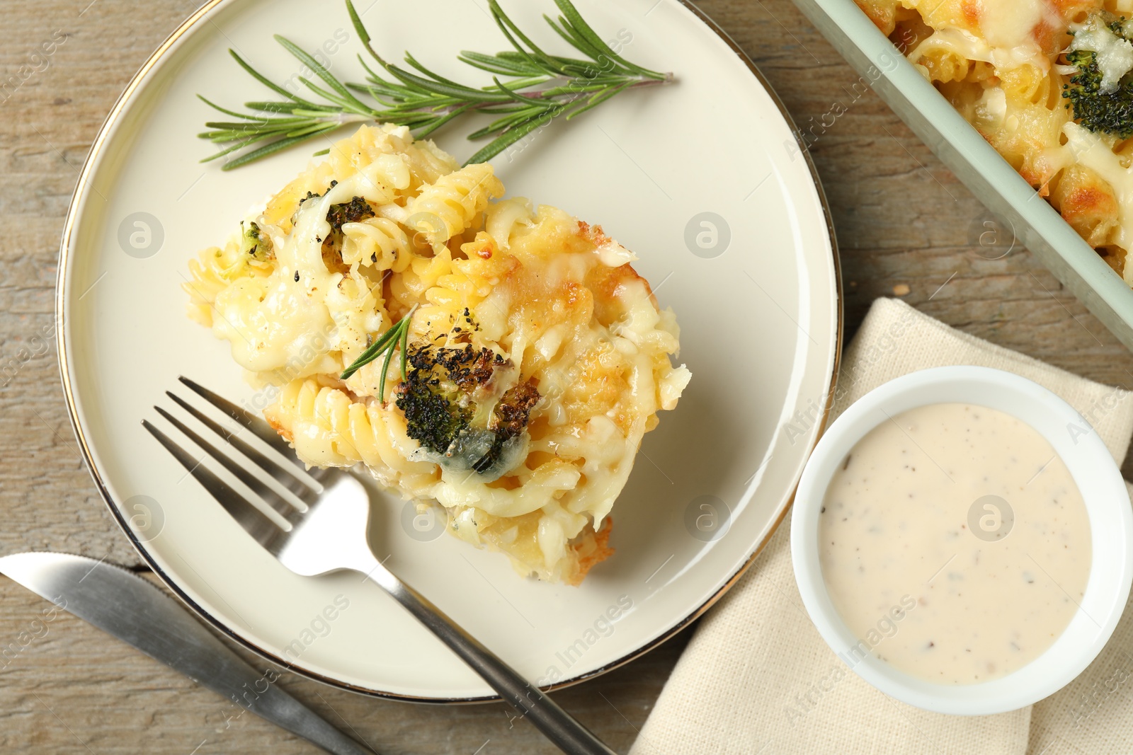 Photo of Tasty pasta casserole with cheese and broccoli served on wooden table, flat lay