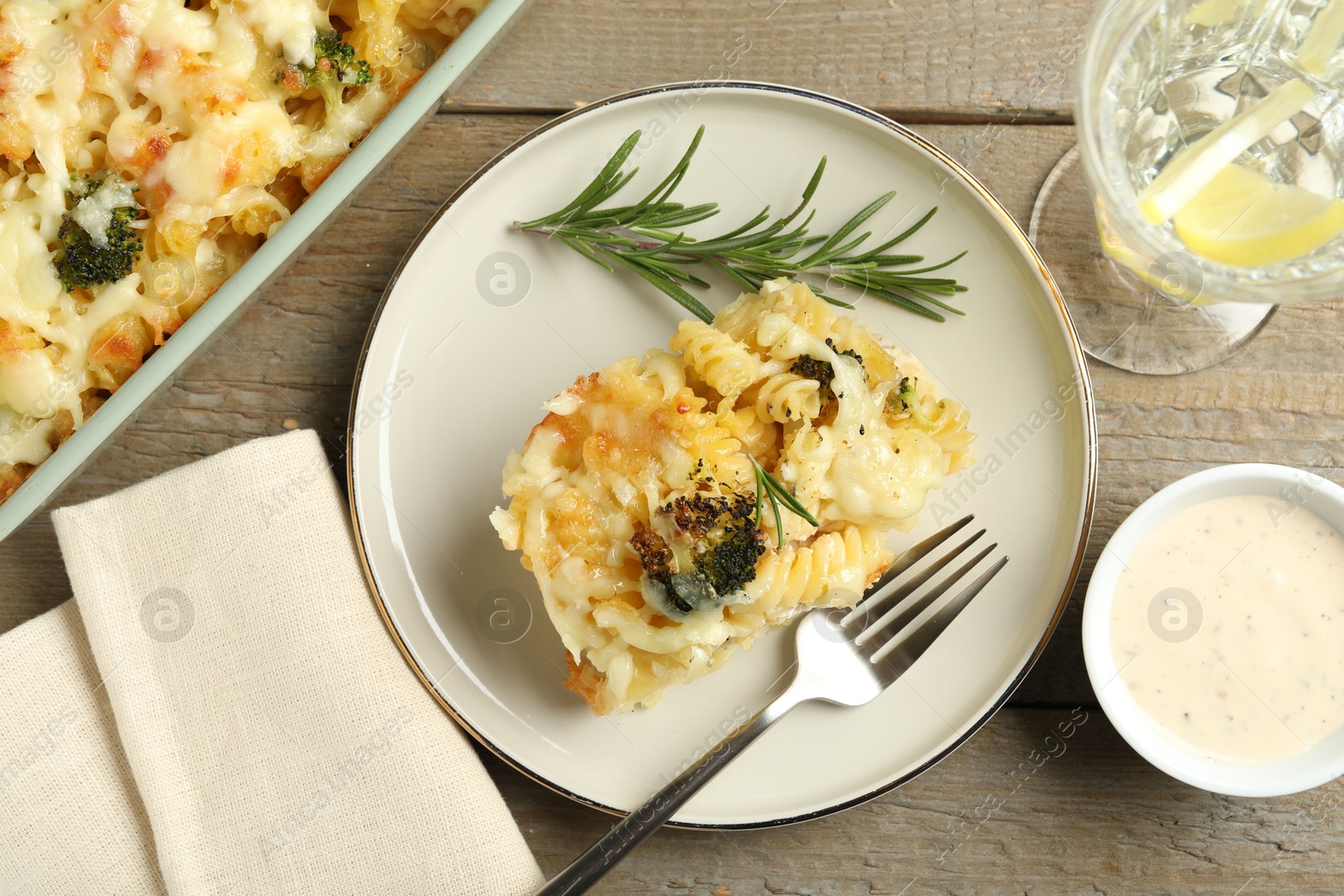 Photo of Tasty pasta casserole with cheese and broccoli served on wooden table, flat lay