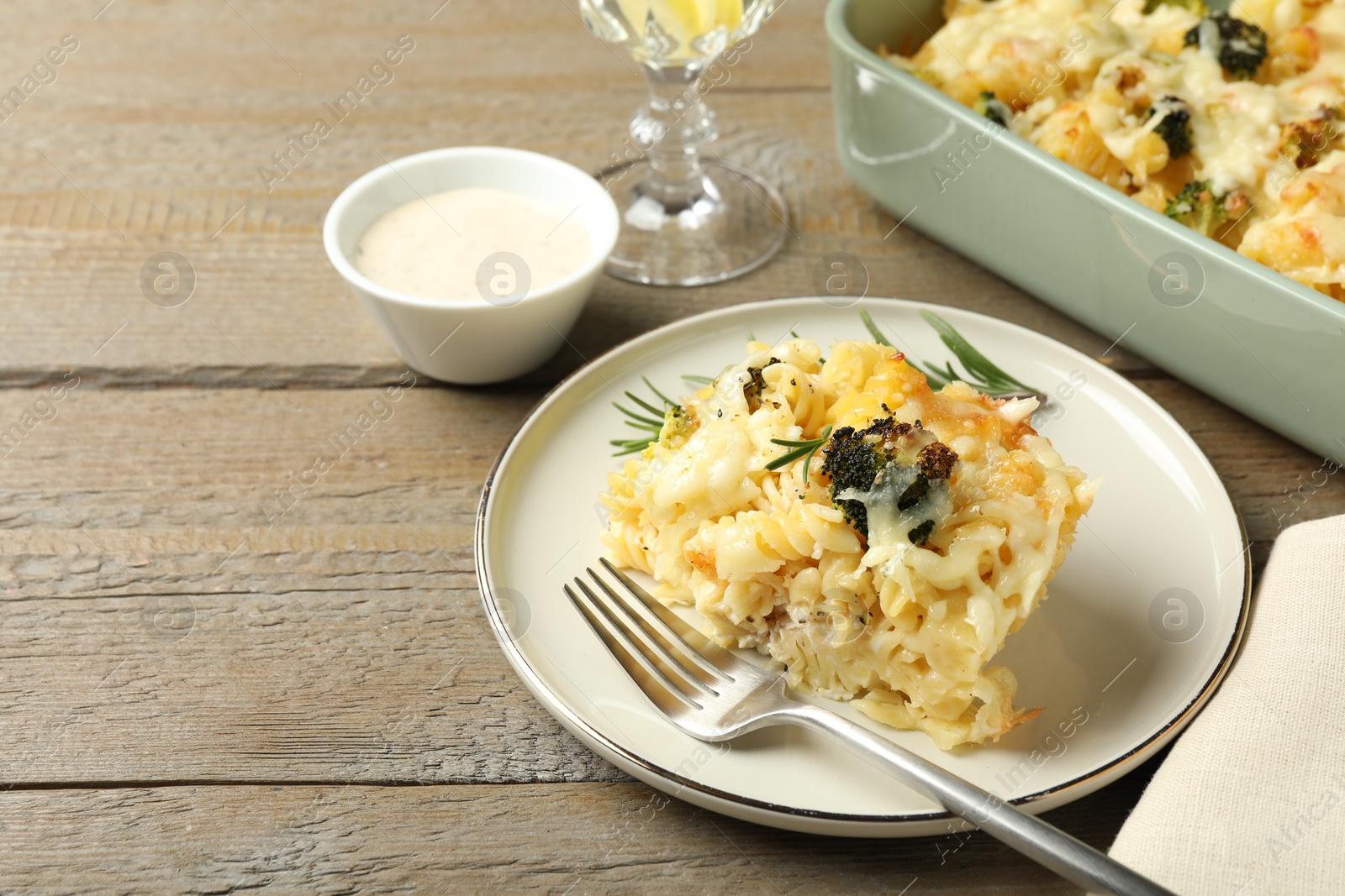 Photo of Tasty pasta casserole with cheese and broccoli served on wooden table, closeup. Space for text