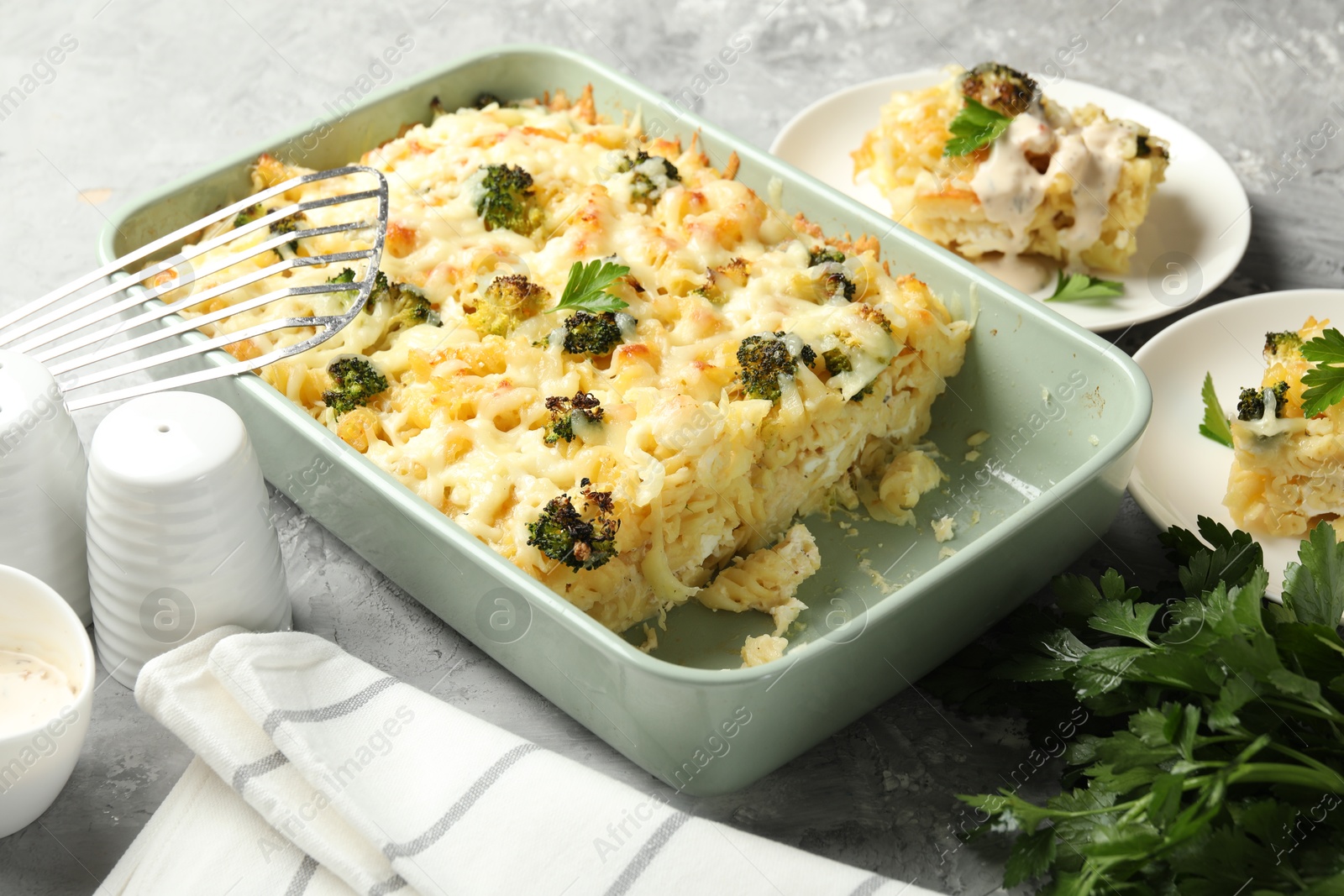 Photo of Tasty pasta casserole with cheese, broccoli and parsley on grey table, closeup