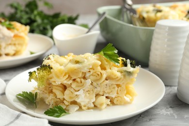 Photo of Tasty pasta casserole with cheese and broccoli served on grey table, closeup