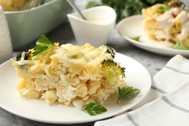 Photo of Tasty pasta casserole with cheese and broccoli served on grey table, closeup