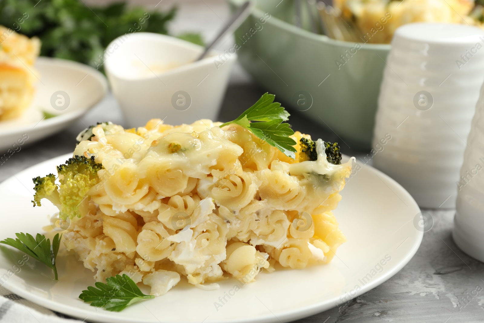 Photo of Tasty pasta casserole with cheese and broccoli served on grey table, closeup