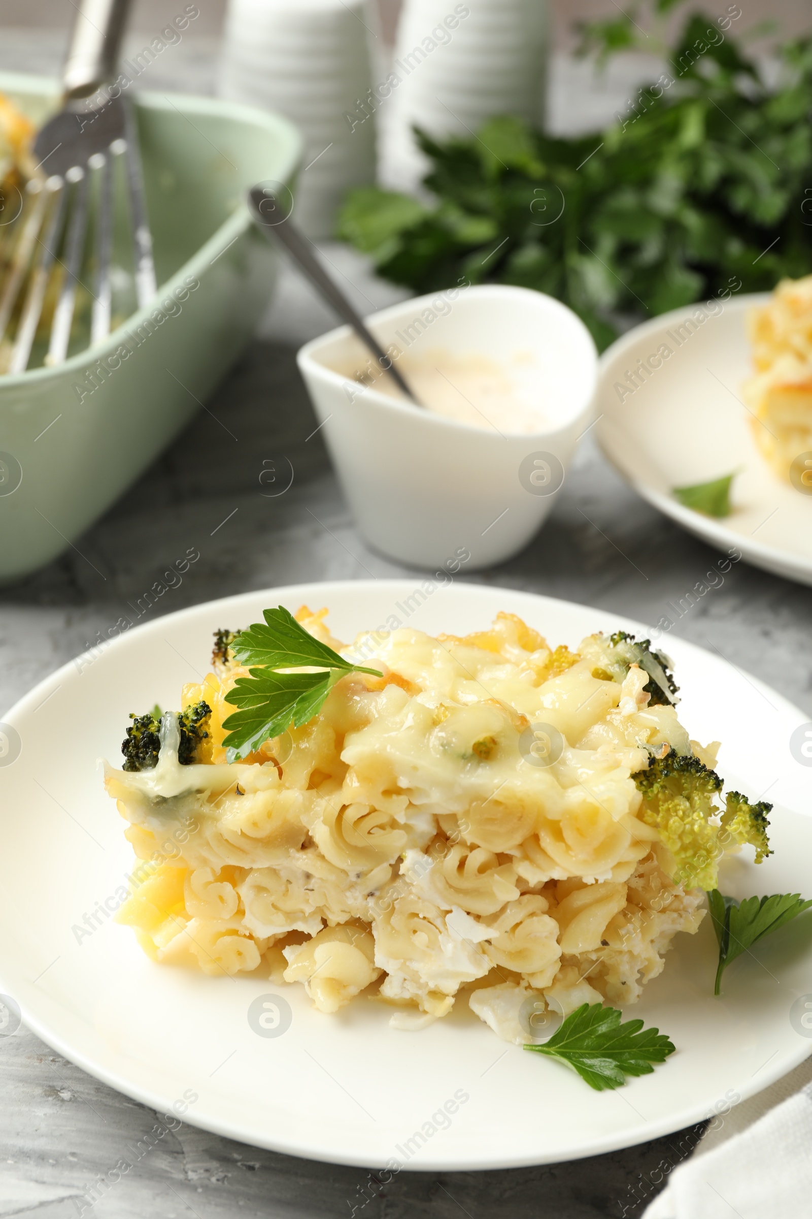 Photo of Tasty pasta casserole with cheese and broccoli served on grey table, closeup