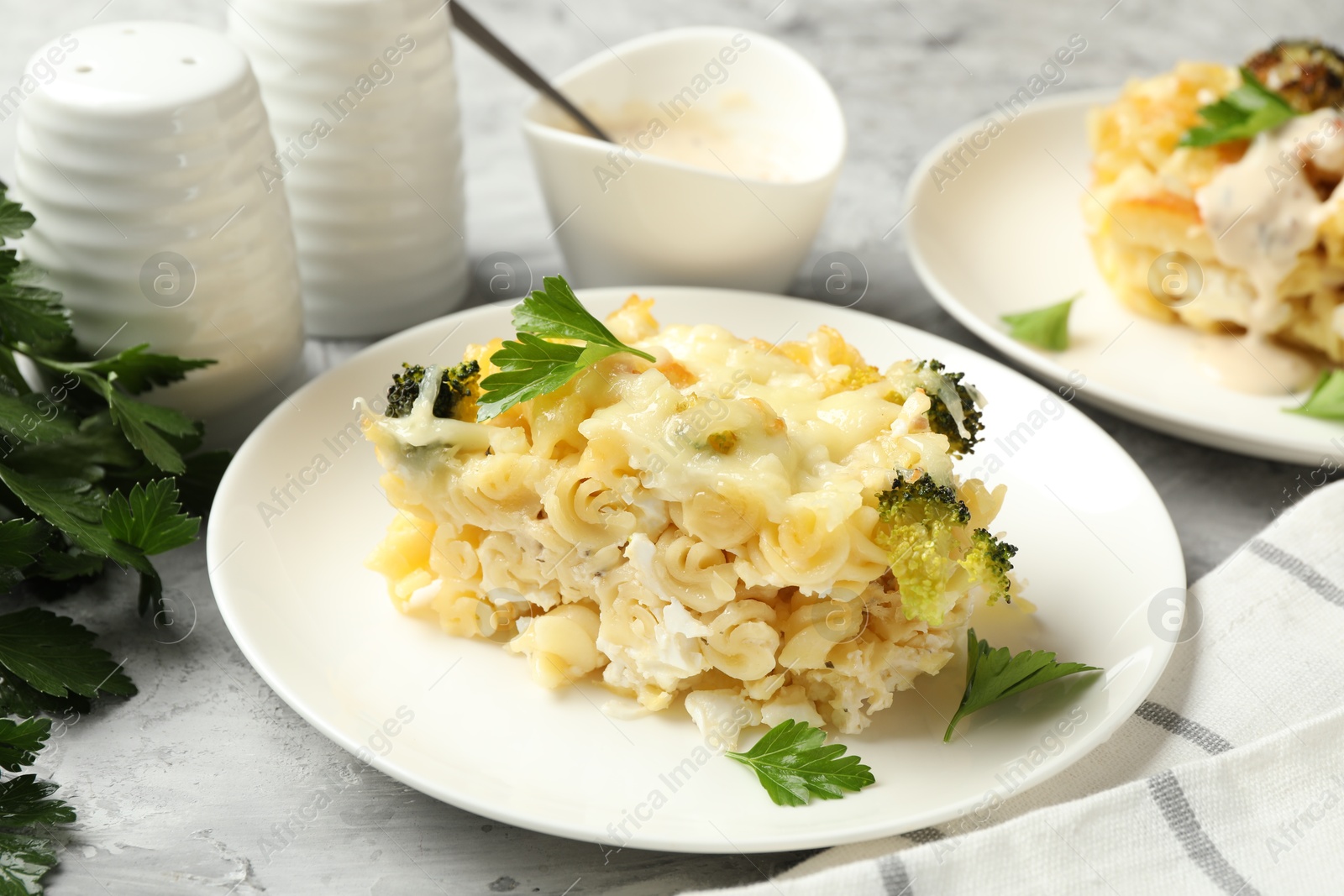 Photo of Tasty pasta casserole with cheese and broccoli served on grey table, closeup