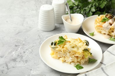 Photo of Tasty pasta casserole with cheese and broccoli served on grey table, closeup. Space for text