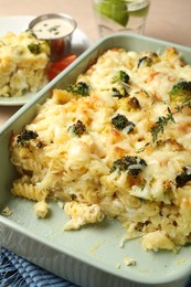 Photo of Tasty pasta casserole with cheese and broccoli in baking dish on wooden table, closeup